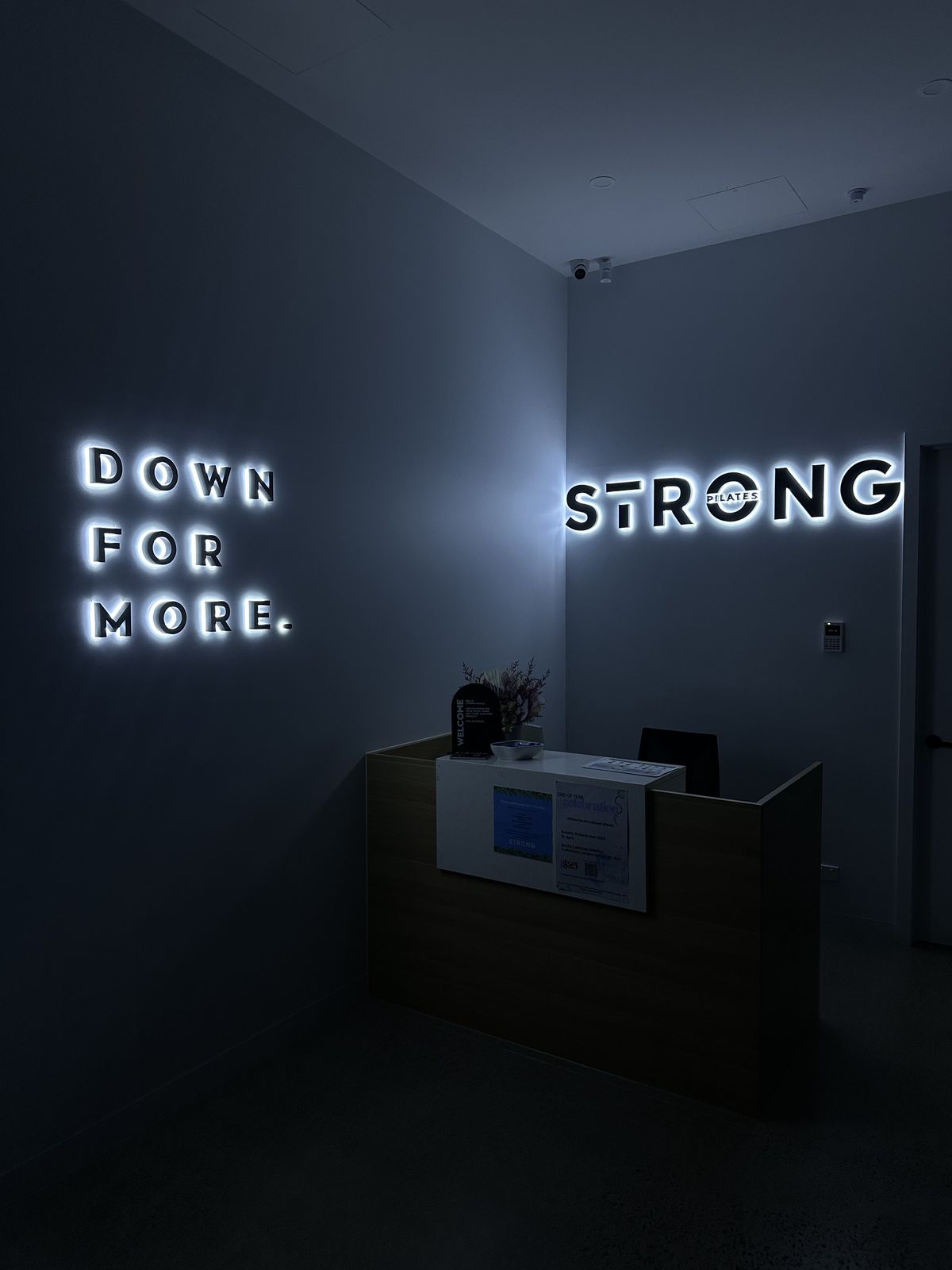 Illuminated Strong lettering and Down For More sign in a studio foyer