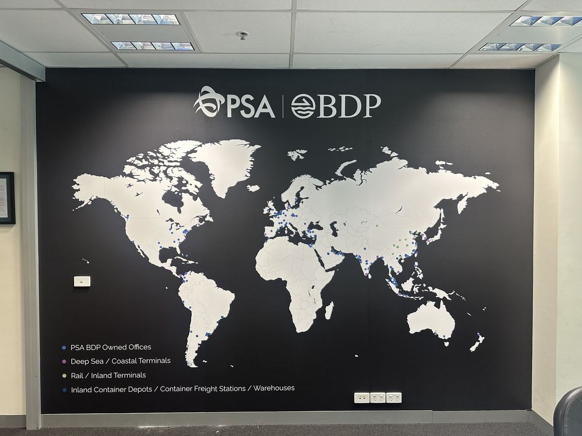 Printed world map wall graphic with company logo and office locations key in an office