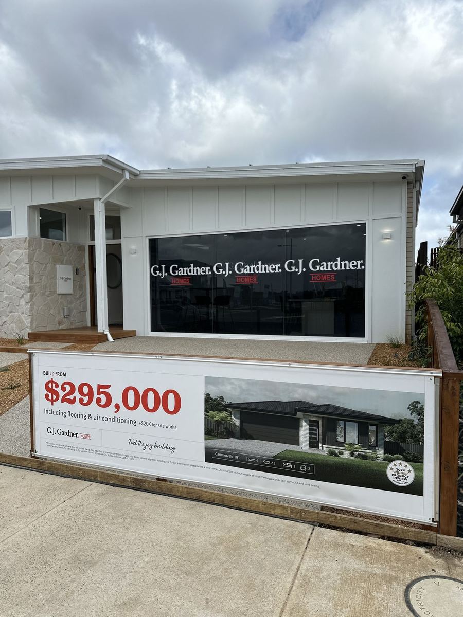GJ Gardner Homes window lettering and fence price banner at a display home
