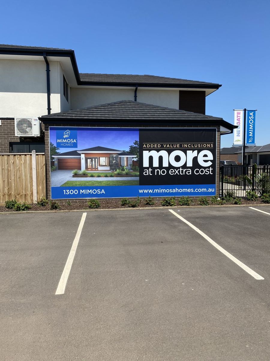Large banner with a home render on a display home garage wall beside visitor parking