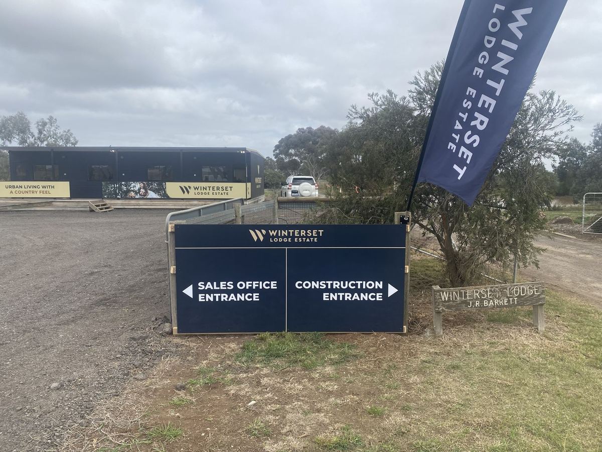 Navy estate sign with arrows to the sales office entrance and the construction entrance