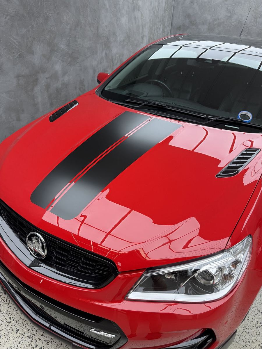 Red Holden sedan with a black bonnet stripe wrap