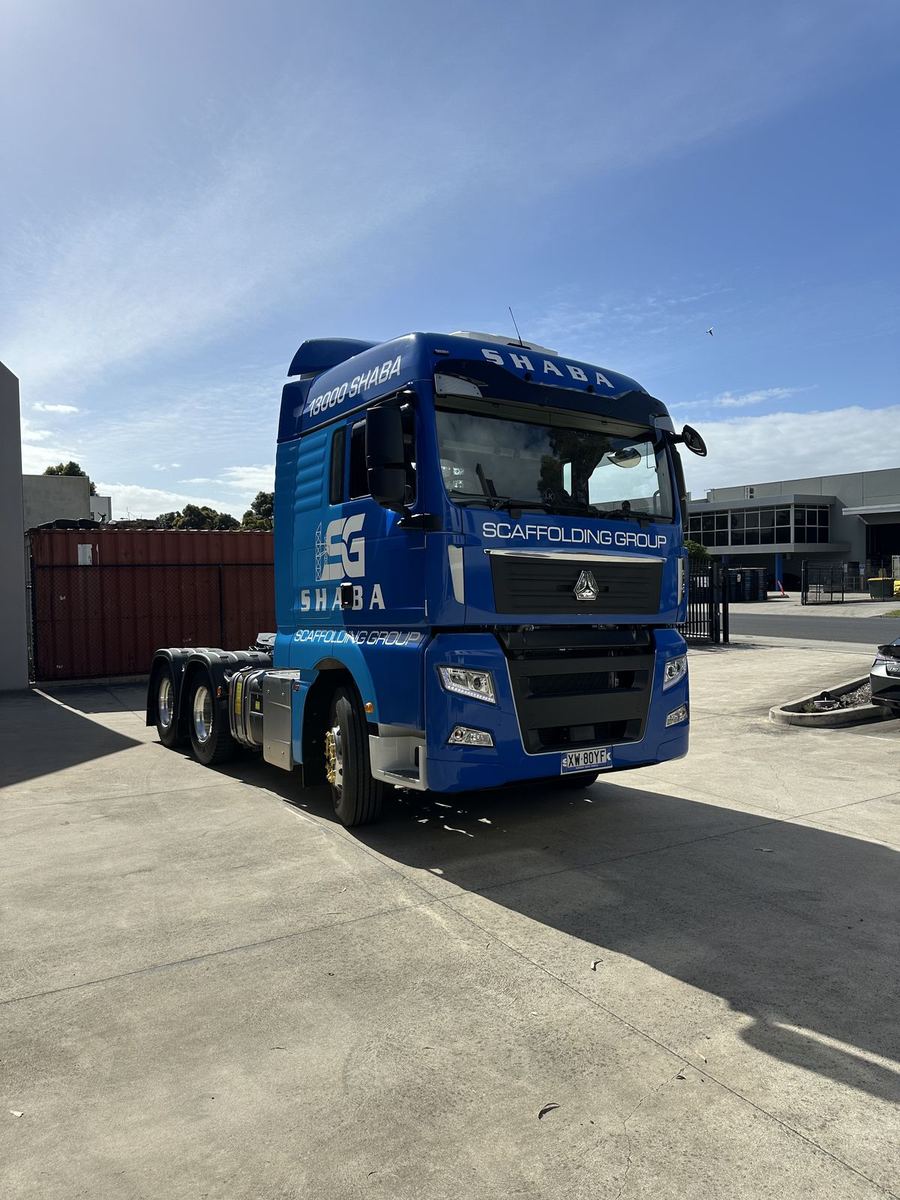 Blue prime mover truck with a full wrap and scaffolding company branding