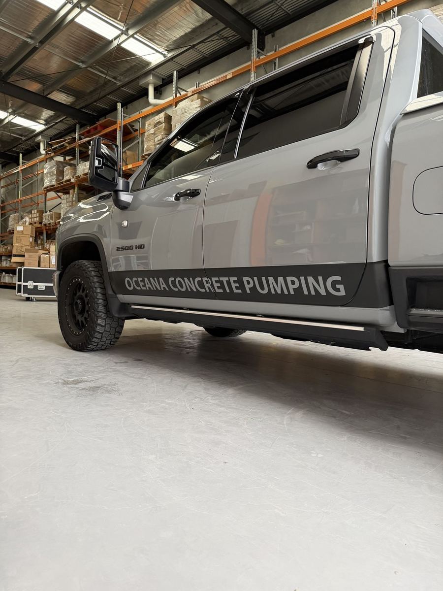 Oceana Concrete Pumping lettering on a black lower door band of a grey pickup