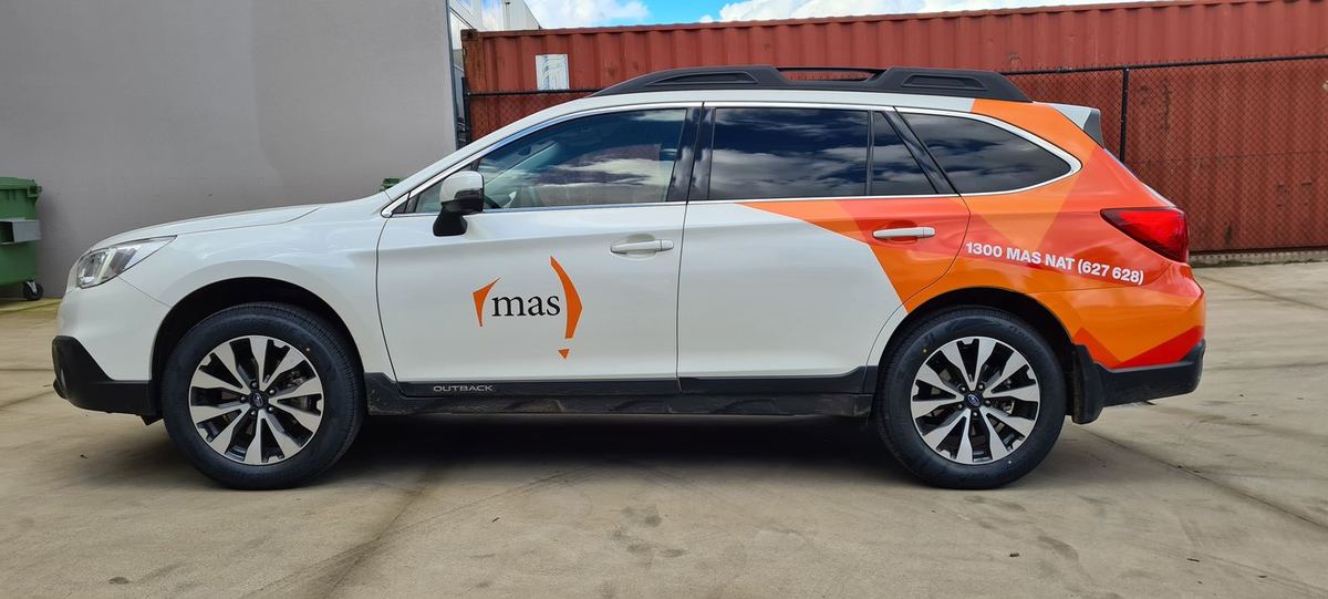 Printed orange rear-quarter graphics and door logo on a white Subaru Outback wagon